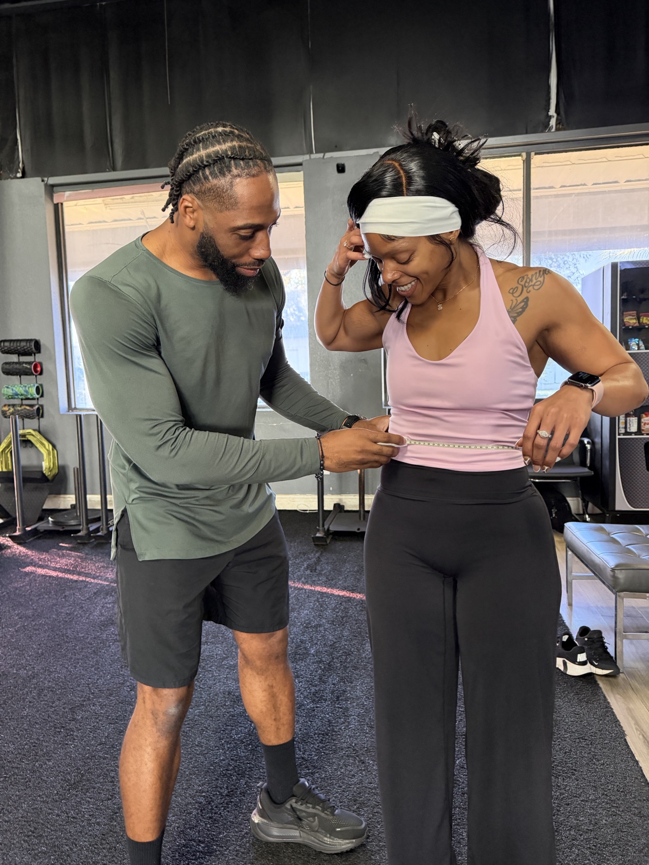 Coach measuring a client's waist during a check-in at Look Who's Fit