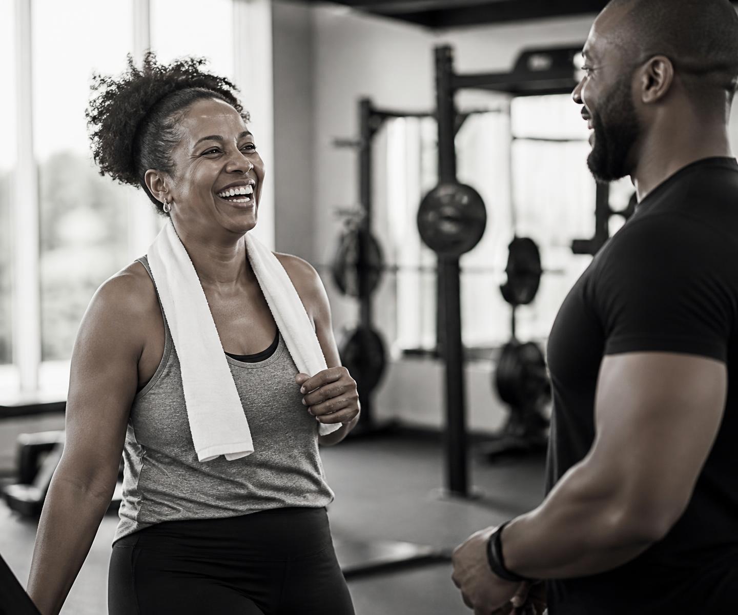 A member laughing with her trainer after finishing a session